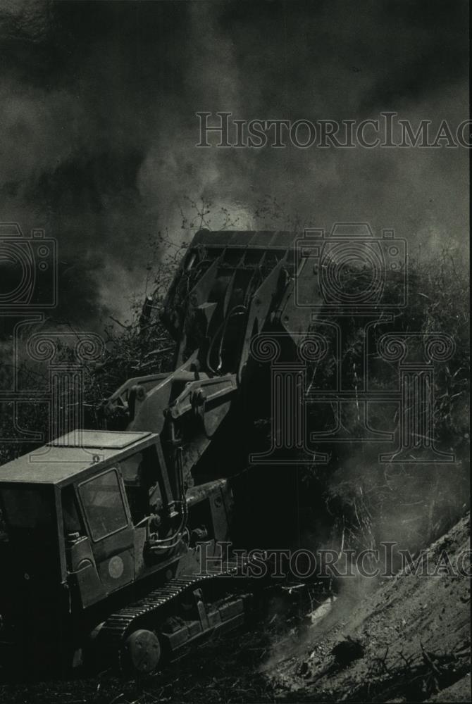 1990 Press Photo worker drives branches into a fire with bulldozer in MIlwaukee - Historic Images