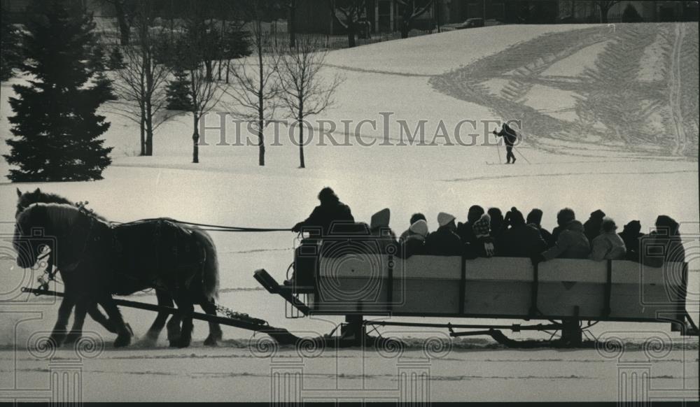 1991 Press Photo Sled and skier glide through the snow in Madison, Wisconsin - Historic Images