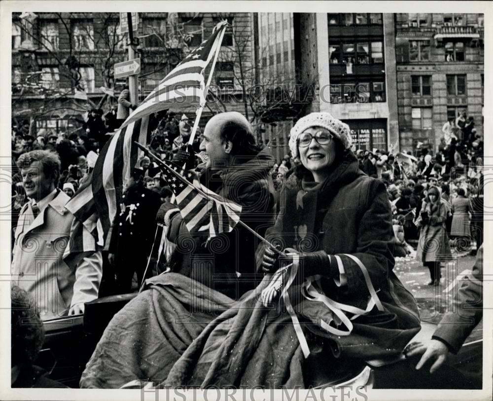 Press Photo Man and Woman wave American flags during parade - Historic Images