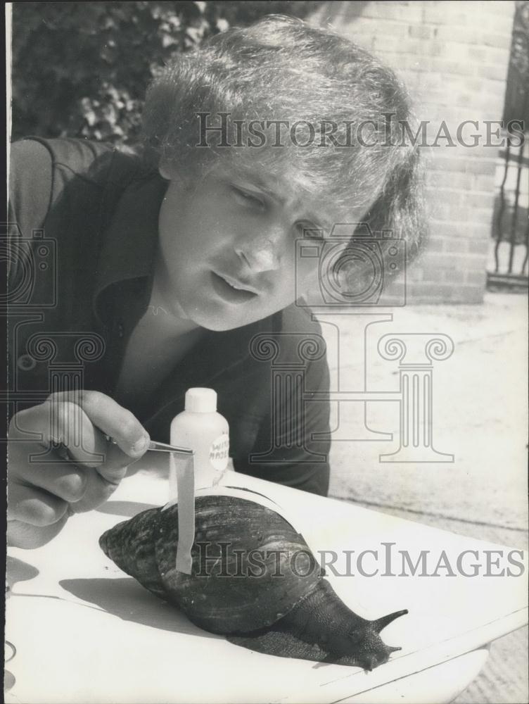 Press Photo Chris Hudson measures a huge snail found in W. Africa - Historic Images