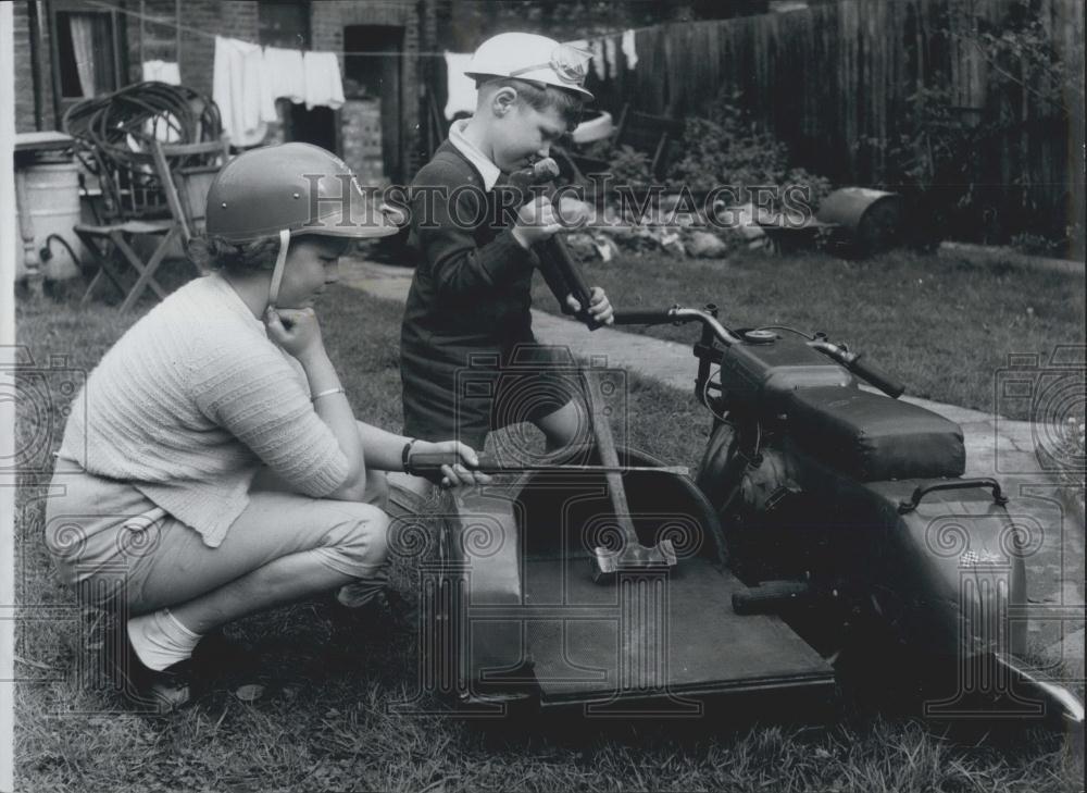 Press Photo Mechanics at large Geoff and Marian do a few running repairs - Historic Images