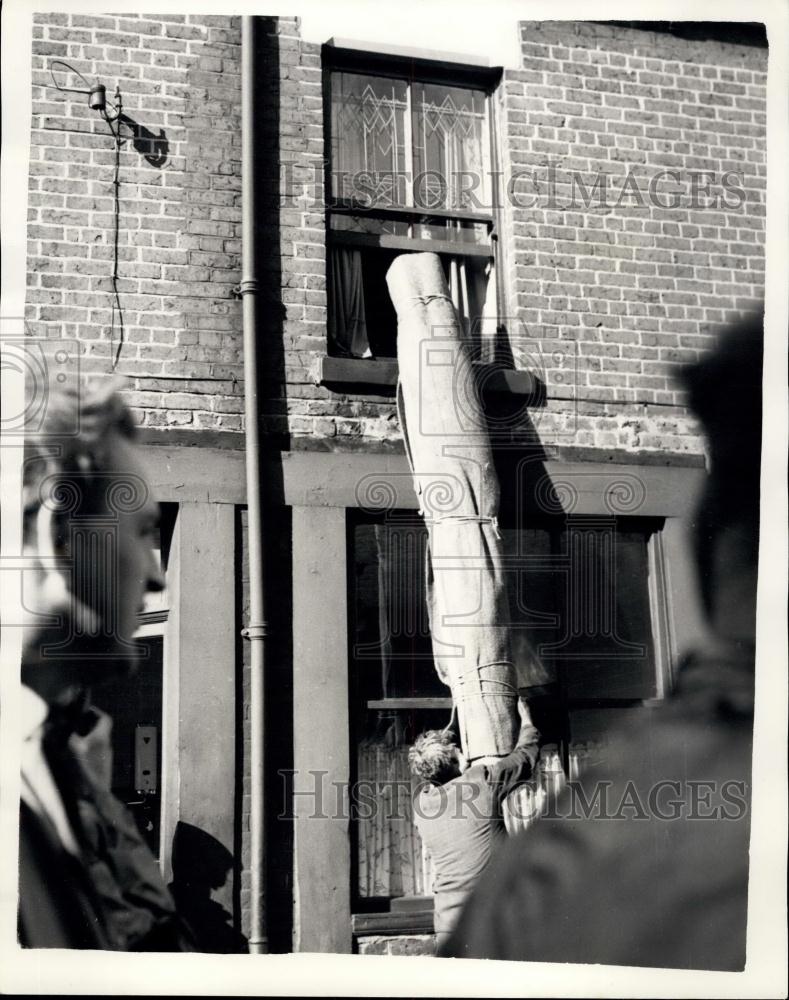 1957 Press Photo Carpets being handed through one of the widows of a house - Historic Images