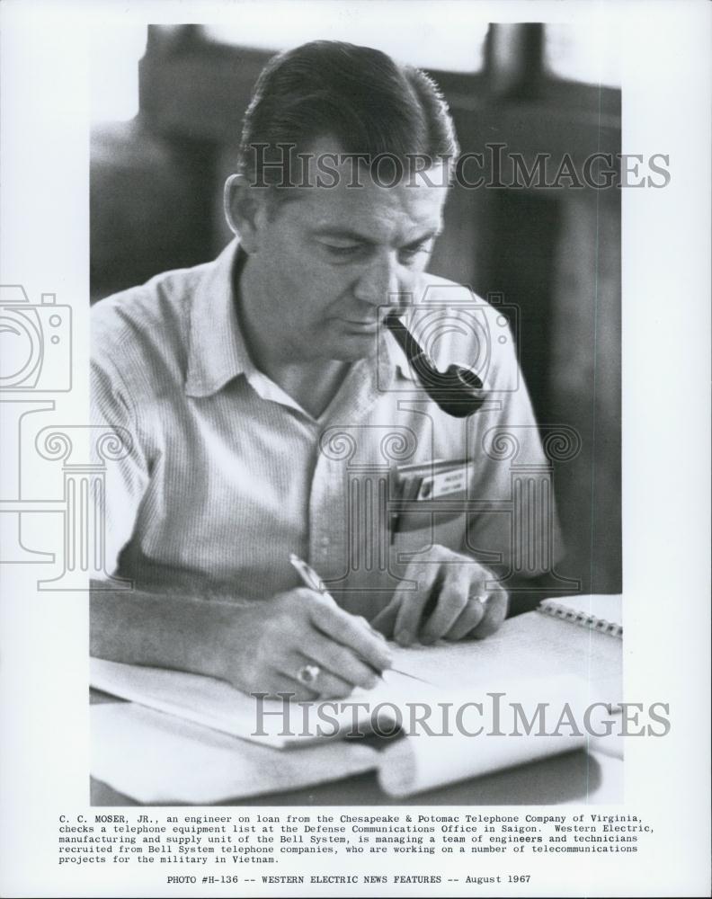 Press Photo C.C. Moser, Jr. An engineer checks a telephone equipment list - Historic Images