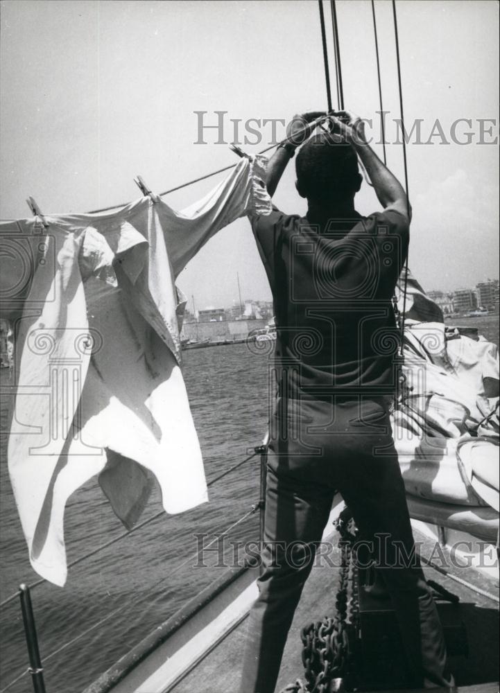 Press Photo Man Hangs Clothes To Dry While On Boat - Historic Images