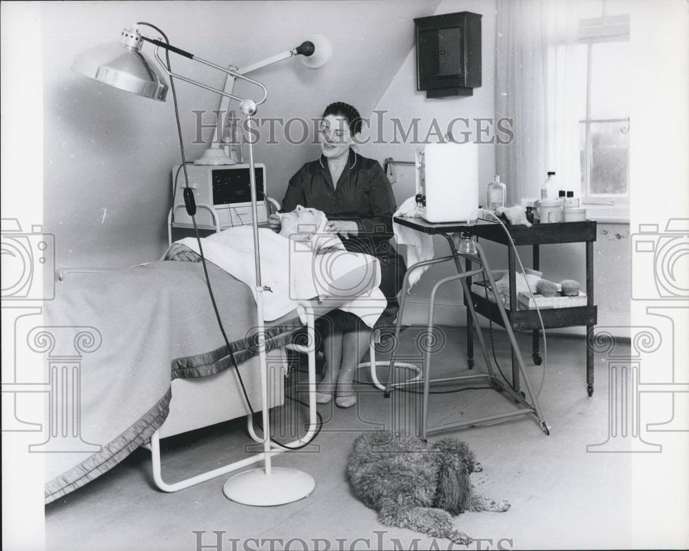 Press Photo Lady Using Machine To Give Customer A Facial Treatment With Poodle - Historic Images