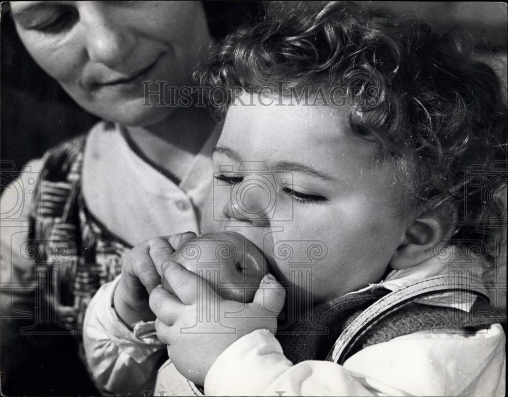 Press Photo Little one trying to eat an apple. - Historic Images