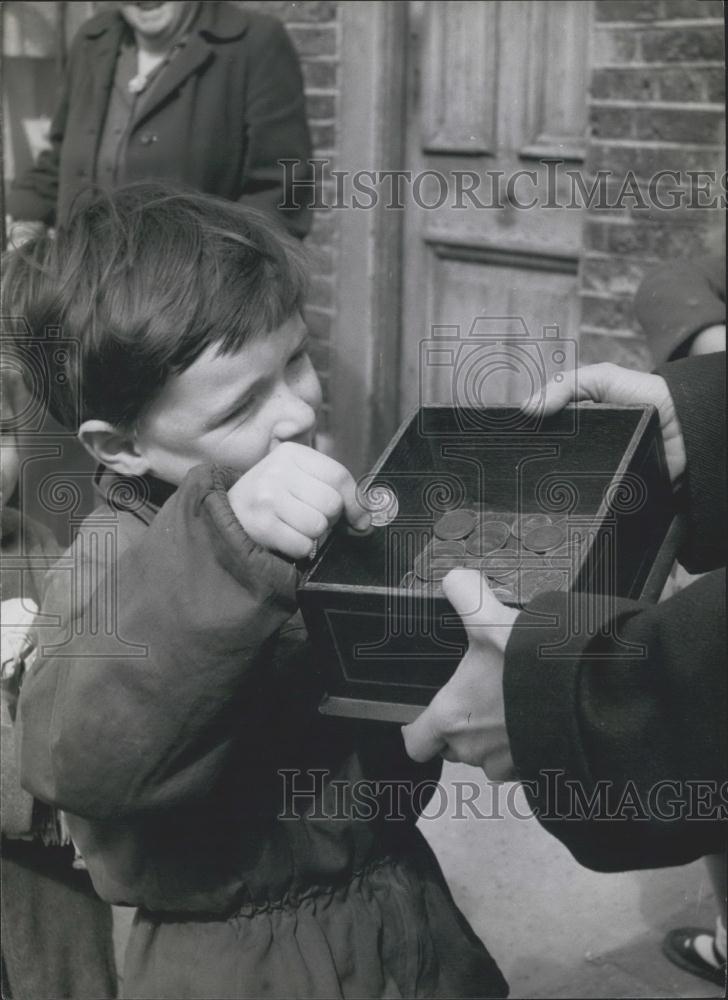 Press Photo Little Boy Matthew Hannan Putting Farthing In Bundle Box In Bow - Historic Images