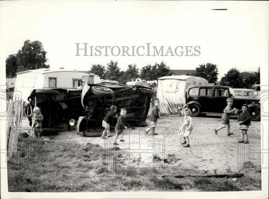 Press Photo Kids play next to overturned vehicles - Historic Images