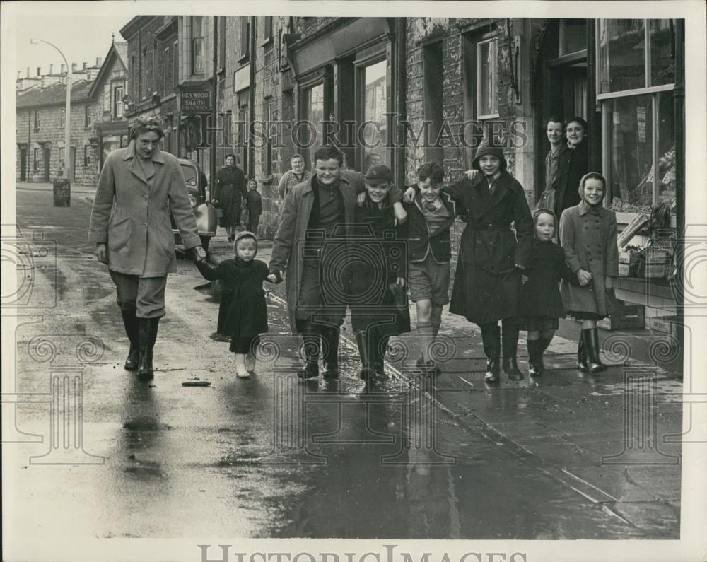 1964 Press Photo Mothers Escorted Children To School Over The Muddy Streets At K - Historic Images