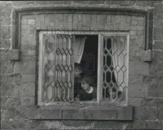1968 Press Photo Girl looks out of window after father barricaded family in home - Historic Images