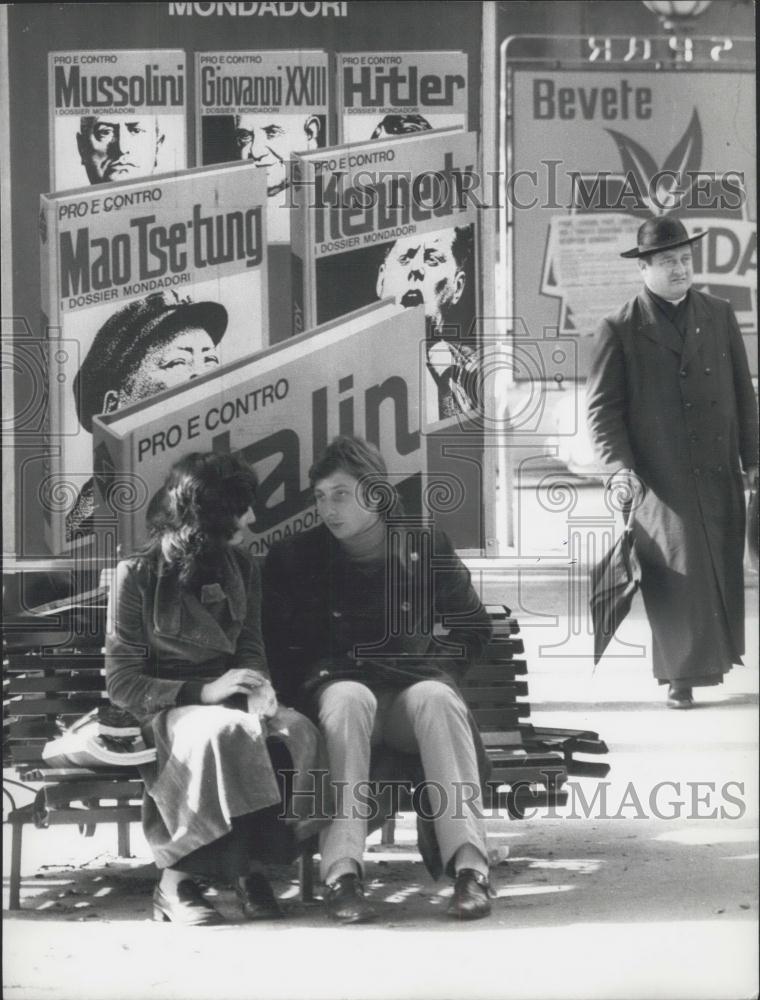 Press Photo People on a bench under signs - Historic Images