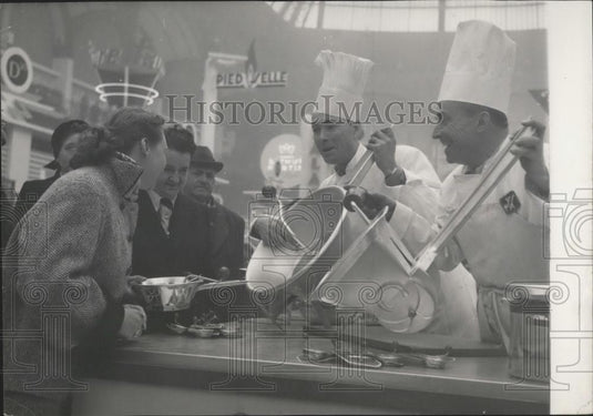 1953 Press Photo Demonstrator Shows Difference Between Two "Moulinettes" (Mills) - Historic Images