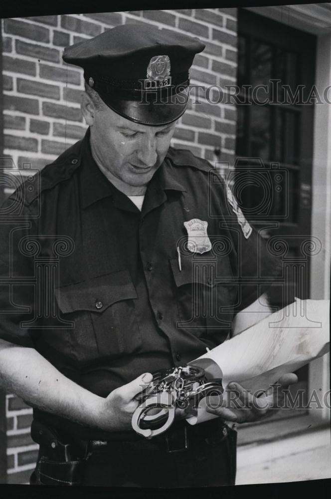 1968 Press Photo Officer John Smith holding handcuff used in bank robbery - Historic Images