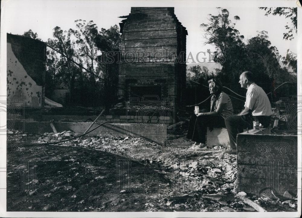 1971 Press Photo Couple sit amid the burned remains of their home in California - Historic Images