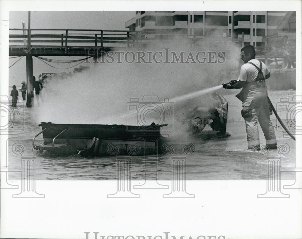 1986 Press Photo Firefighter puts out blaze on boat near Indian Rocks beach, Fla - Historic Images