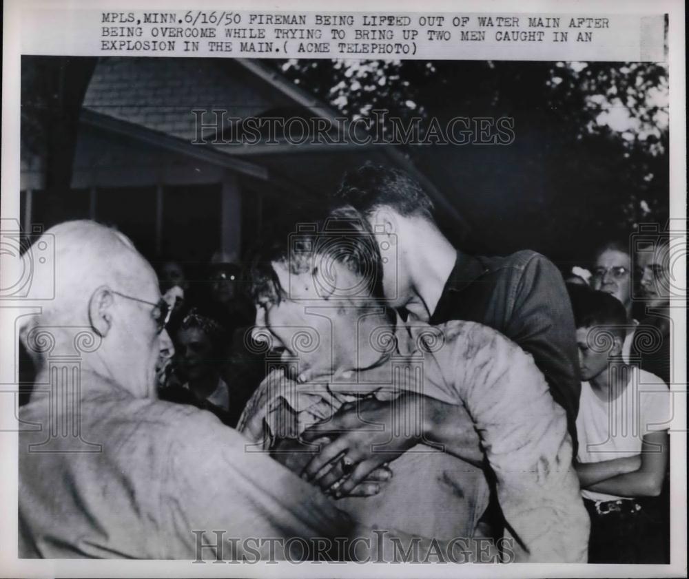 1950 Press Photo fireman lifted out of water main after explosion - nea22808 - Historic Images