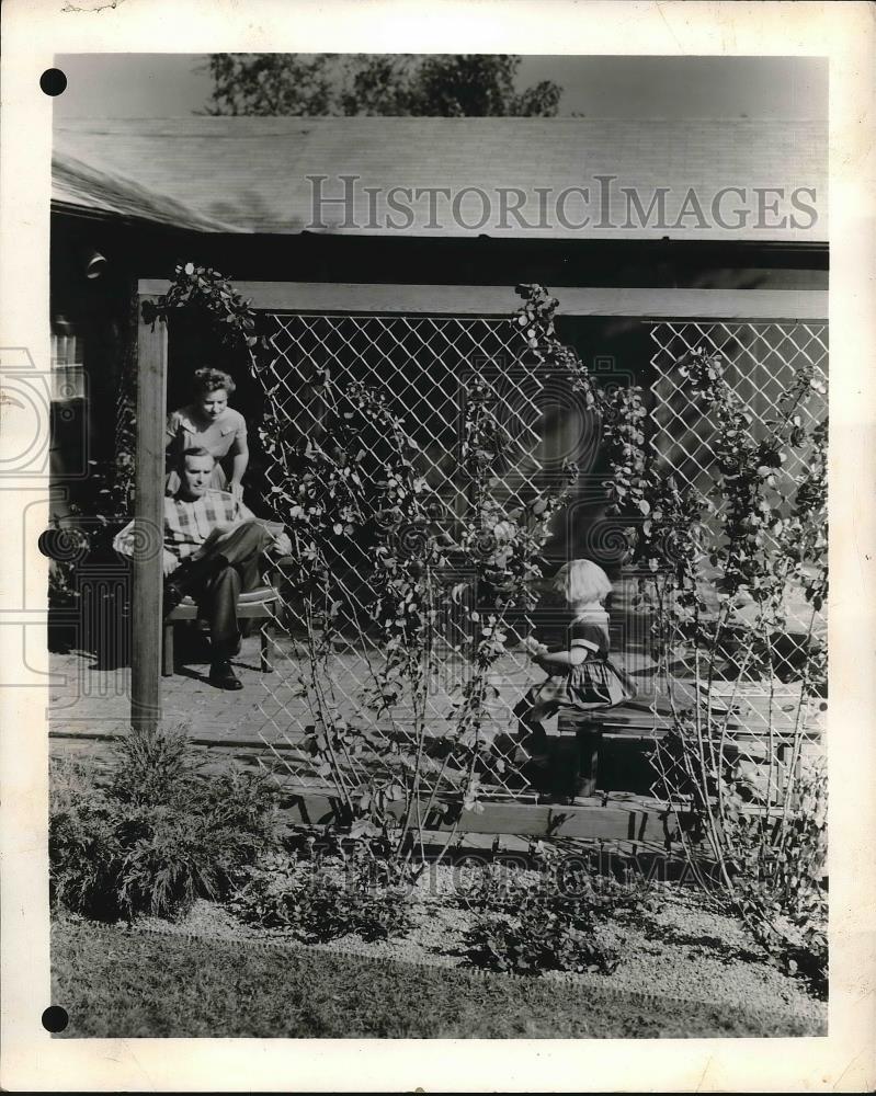 Press Photo Couple With Child Working In Garden By Flower Fence - nea84667 - Historic Images