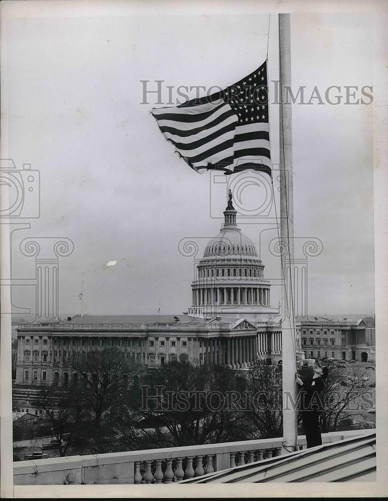1950 Press Photo Policeman Lowering Flag To Half Mast Atop Old House Building - Historic Images
