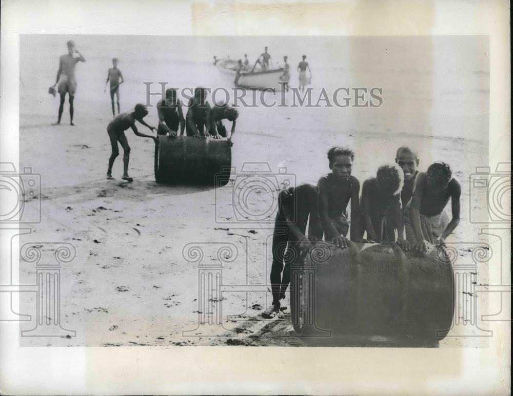 1942 Press Photo New Guniea, natives unload gas drums from boats for US military - Historic Images