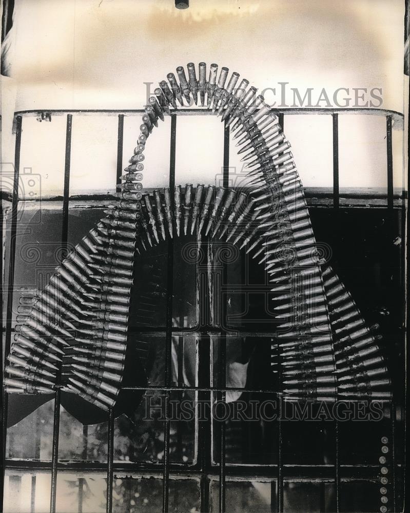 1965 Press Photo Belted Machine Gun Ammunition Is Draped Over Window Bars - Historic Images