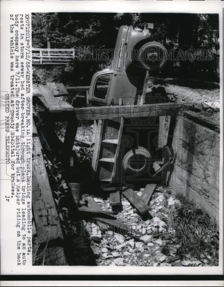 1956 Press Photo Truck hauling auto parts rests in storm sewer broke thru planks - Historic Images