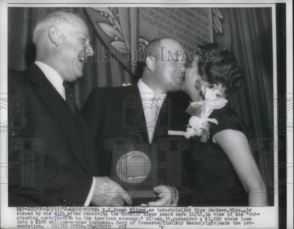 1956 Press Photo Industrialist R. E. Dumas Milner kissed by his wife after - Historic Images