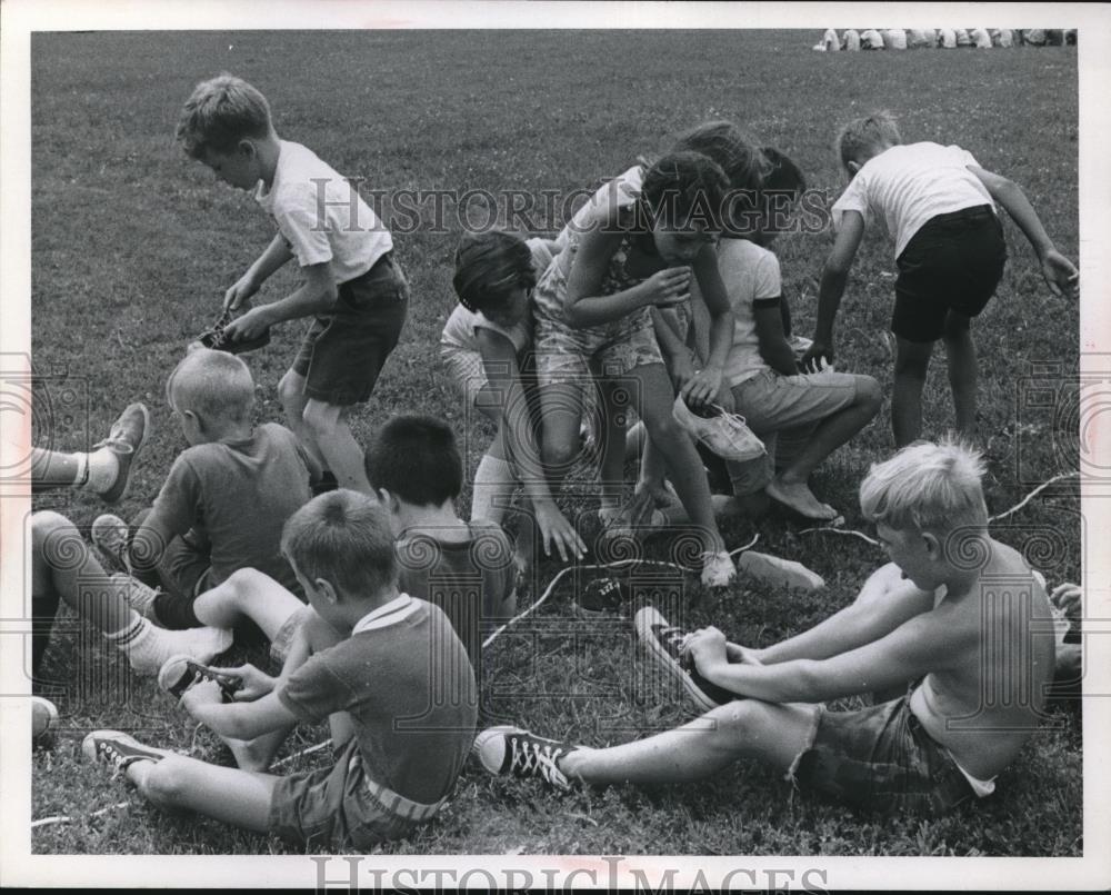 Press Photo Youngsters put on shoes before playing - Historic Images