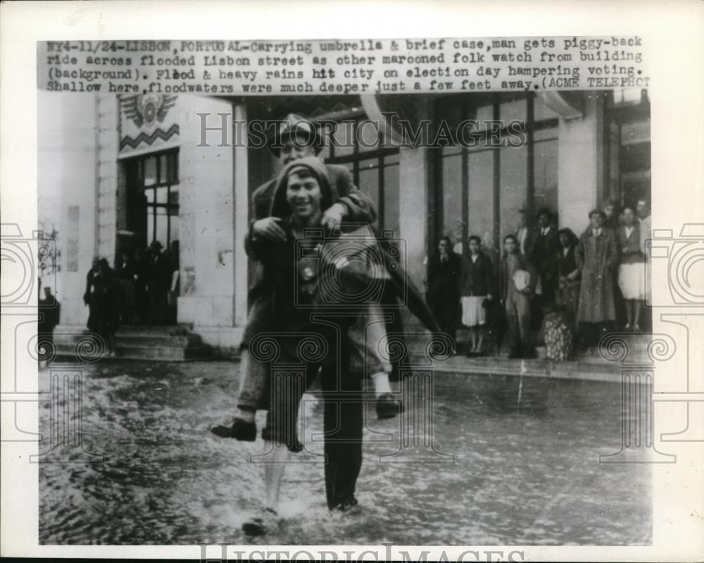 1945 Press Photo Man gets a piggyback ride across flooded Lisbon street - Historic Images