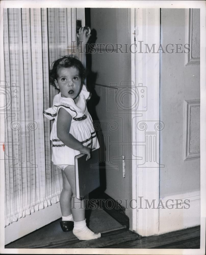 1951 Press Photo A child with a book and a Who Me? look on her face - Historic Images