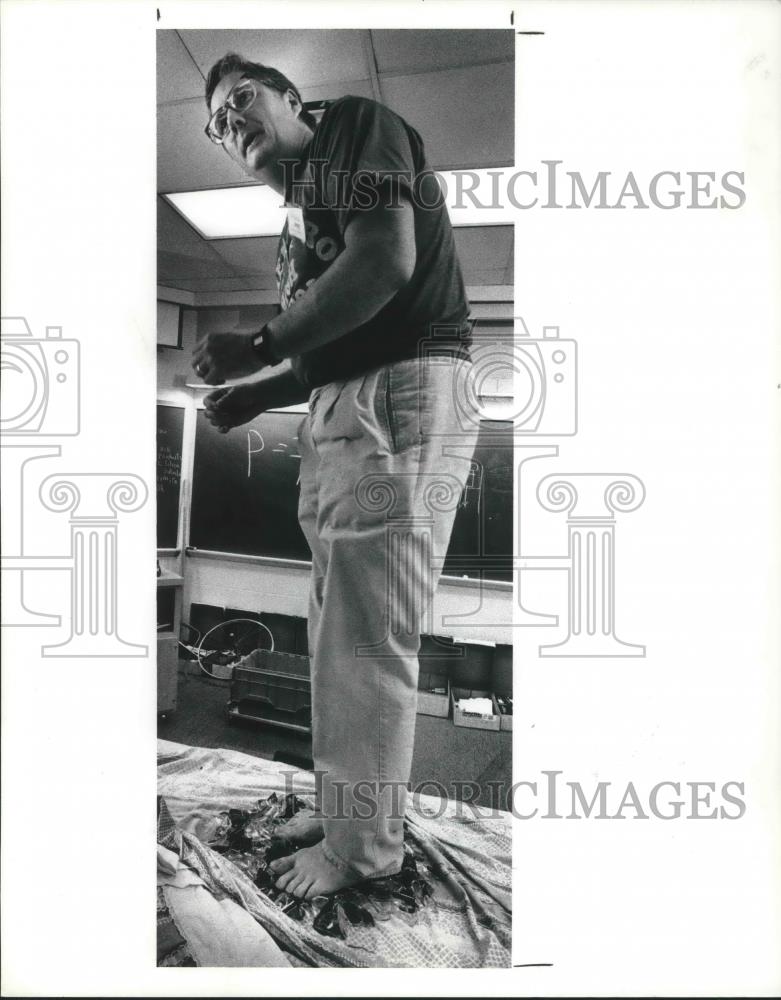 1990 Press Photo Gene Easter stands on broken glass on a desk top - Historic Images