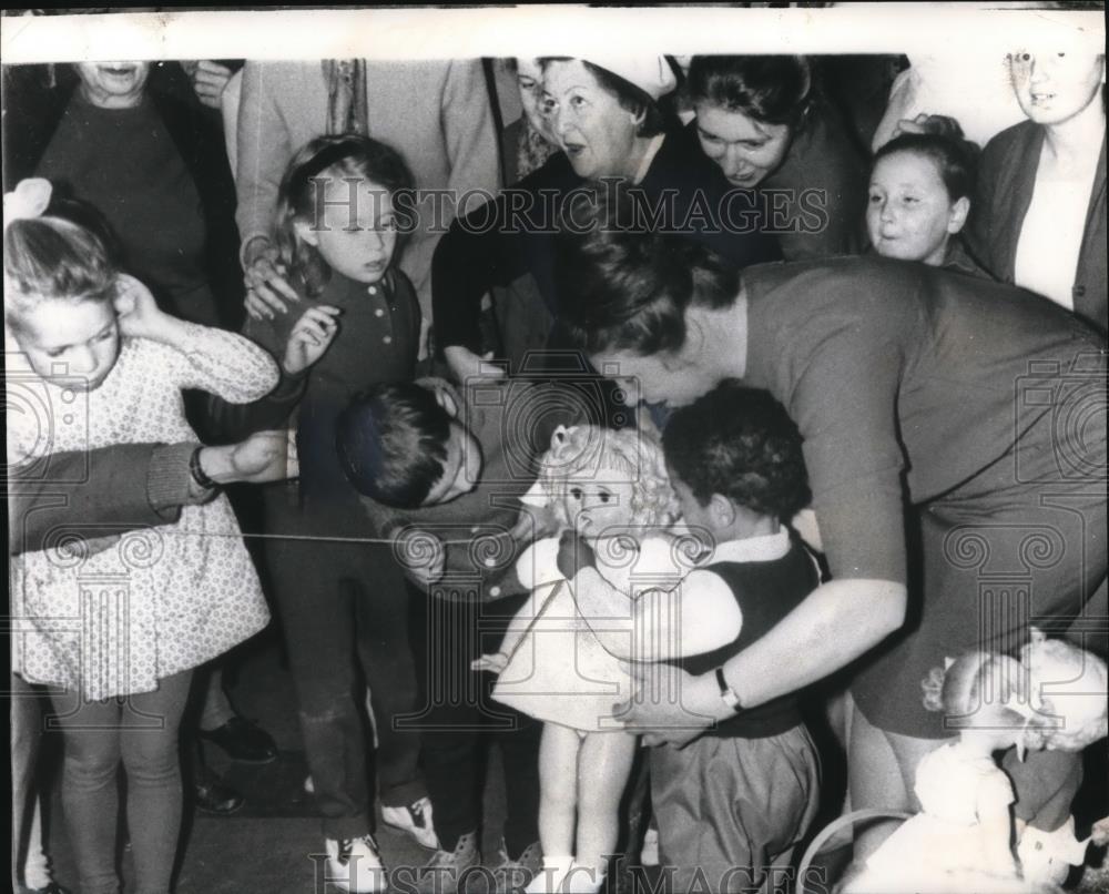 1965 Press Photo Children And Parents Rush Around Doll Being Fed - Historic Images