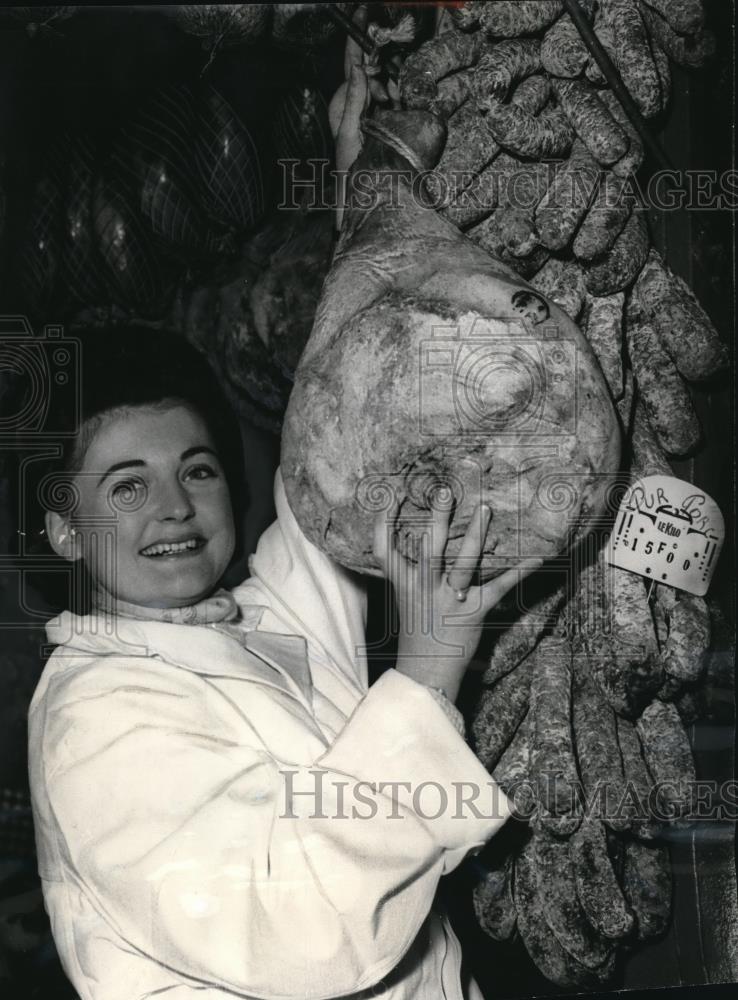 1966 Press Photo Lady says &quot;cheese&quot; while holding ham hanging amid sausages - Historic Images