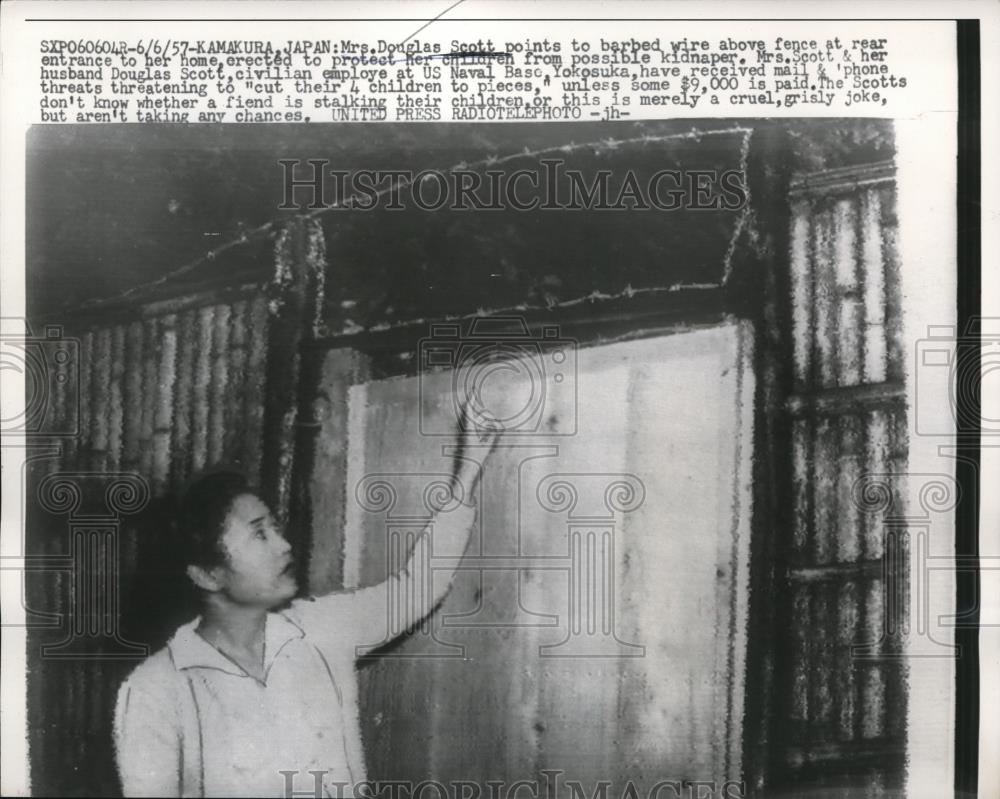 1957 Press Photo Mrs. Douglas Scott points to barbed wire above fence - Historic Images