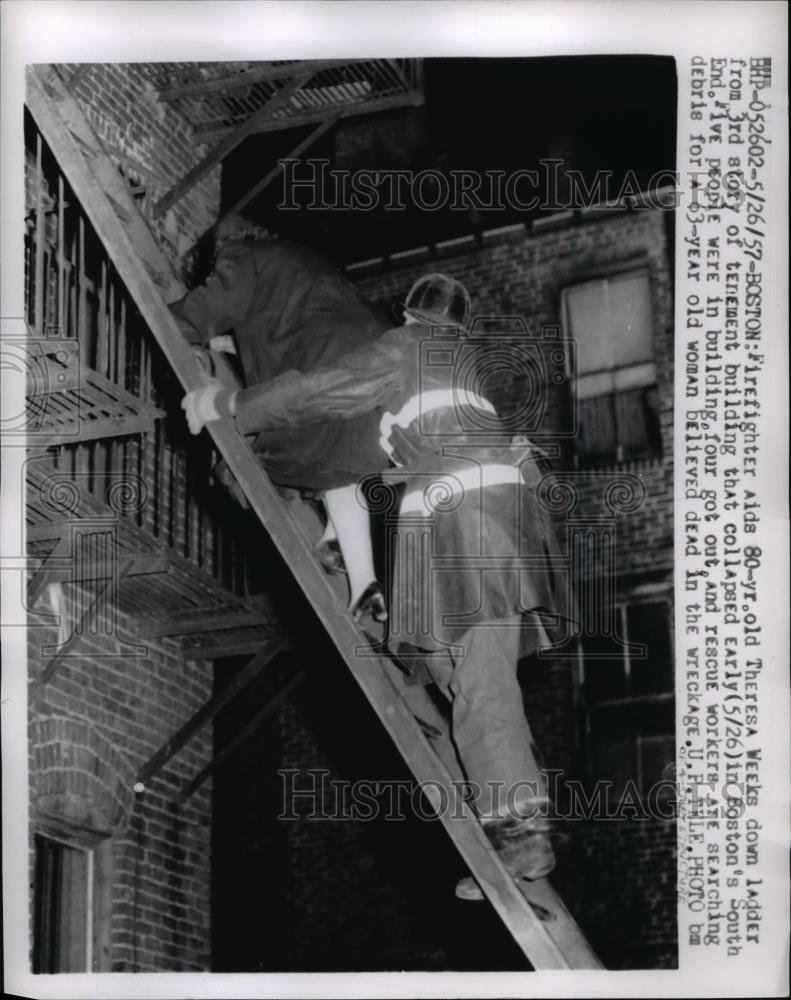 1957 Press Photo Firefighter aids 80 yr old Theresa Weeks down ladder of bldg - Historic Images