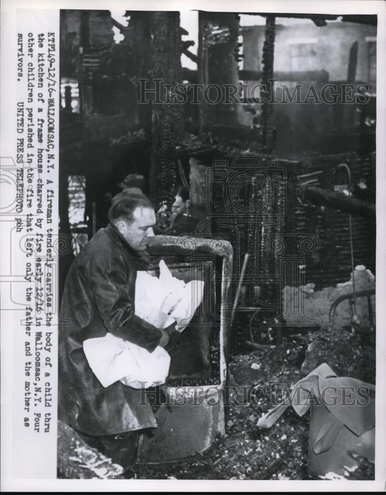 1954 Press Photo A fireman carries the body of a child victim of fire - Historic Images