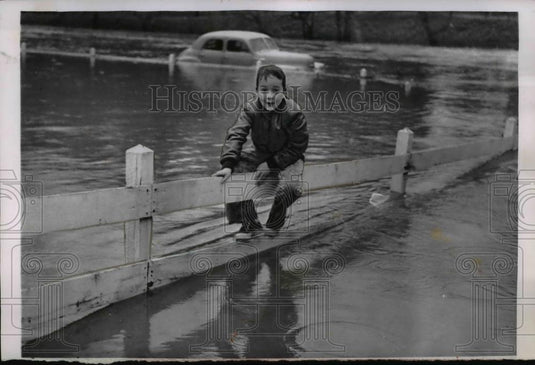 1956 Press Photo Young Hamilton Lokey, Jr. along a fence to keep his feet dry - Historic Images