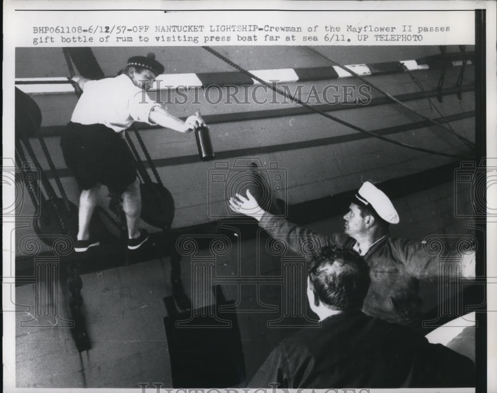 1957 Press Photo Mayflower II crewman passes gift bottle of rum to press - Historic Images