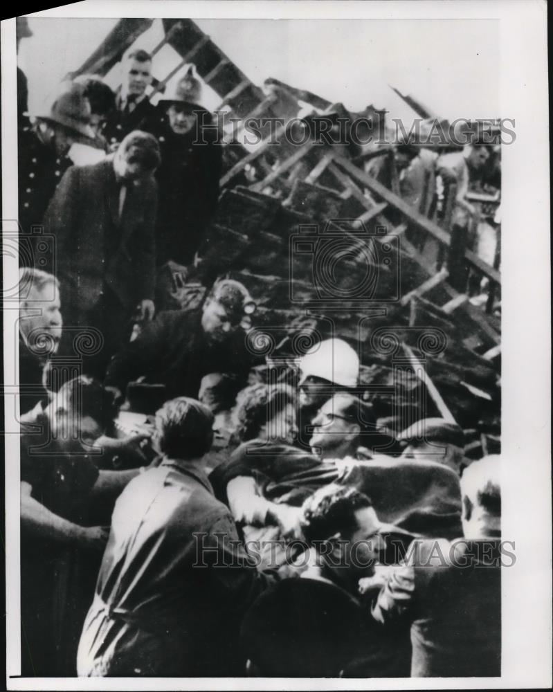 1966 Press Photo Teacher carried by rescue workers from wrecked school - Historic Images