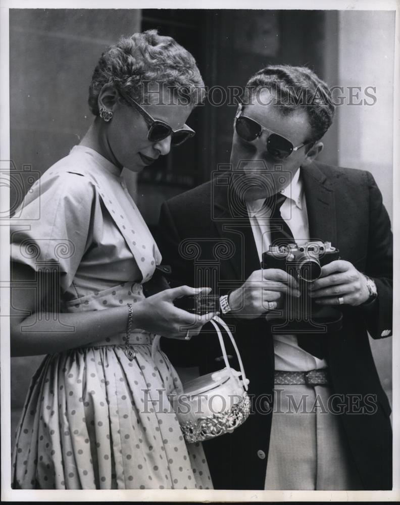 1955 Press Photo Young lady holding exposure meter as male photographer observes - Historic Images