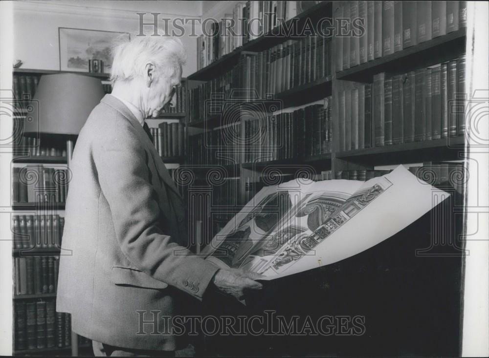 Press Photo Decorator Browsing Through Book In Home Library - Historic Images