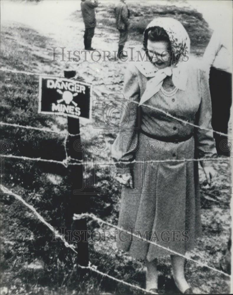 Press Photo Woman Walking Next To Fence With Danger Mines Warning Sign - Historic Images