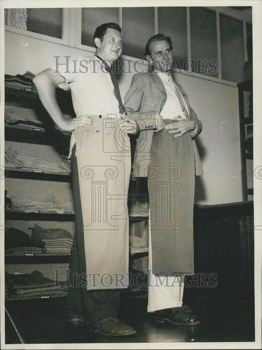 Press Photo Tall Men Holding Normal Man's Pants - Historic Images
