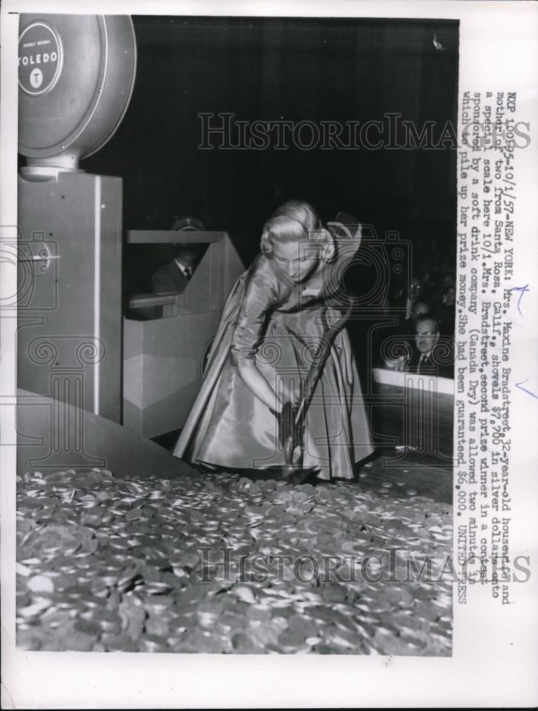 1957 Press Photo Maxine Bradstreet shoveling $7700 in silver dollars onto a - Historic Images