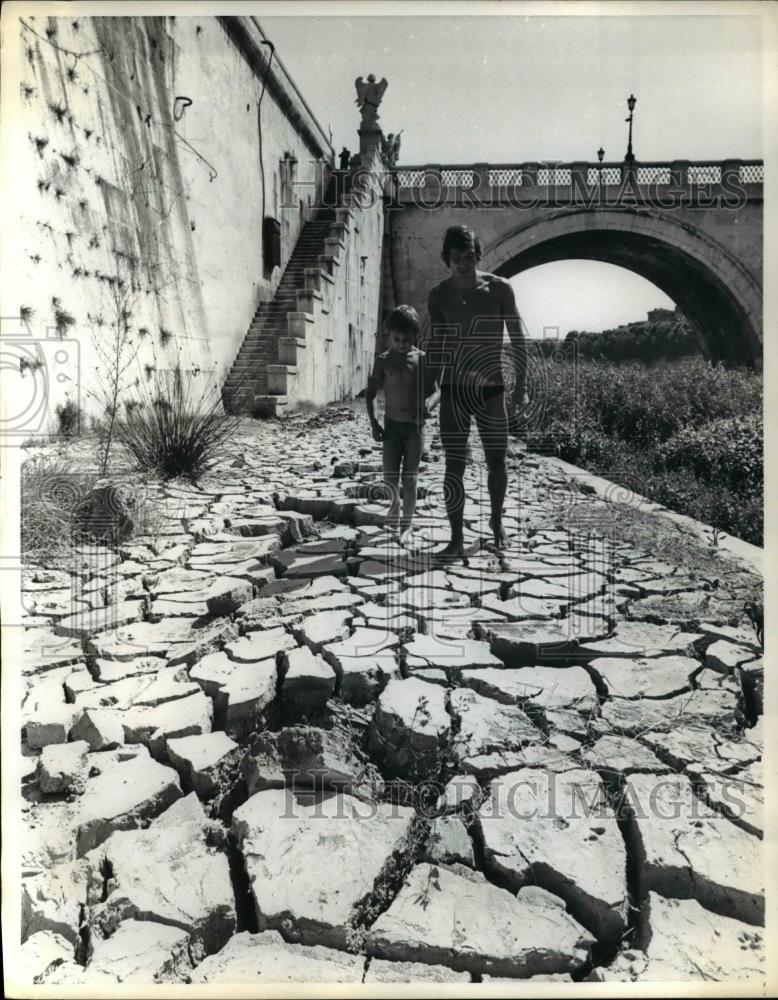 1974 Press Photo A father and son tread carefully across an expanse of dry, - Historic Images