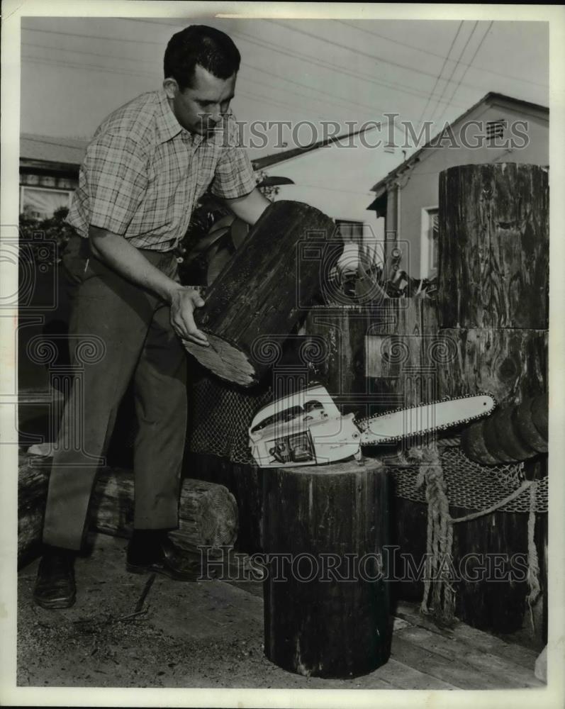 1969 Press Photo A man cutting logs with a chain saw on a farm - Historic Images