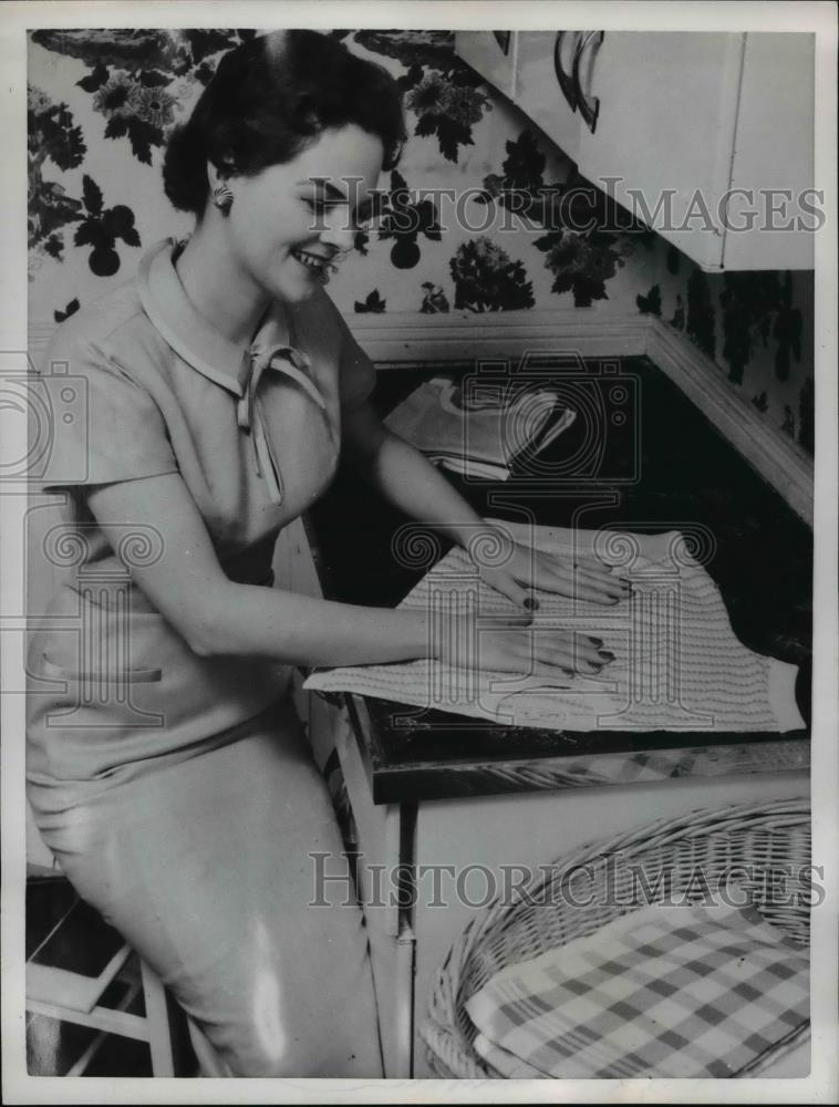 1956 Press Photo Woman smoothing out a knit shirt and folding it for the drawer - Historic Images