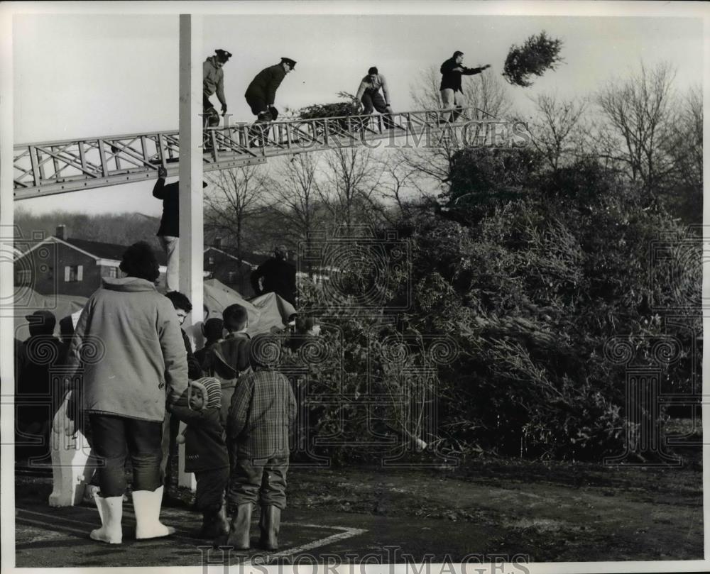 1961 Press Photo Firemen use ladder truck to toss Xmas trees on pile for fire - Historic Images