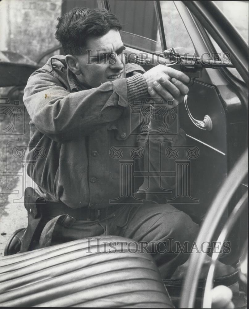 Press Photo Sgt Lloyd takes aim from Behind Window of a Car. - Historic Images