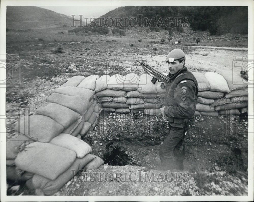 Press Photo A Soldier Stands With His Gun Inside A Wall Of Sand Bags - Historic Images