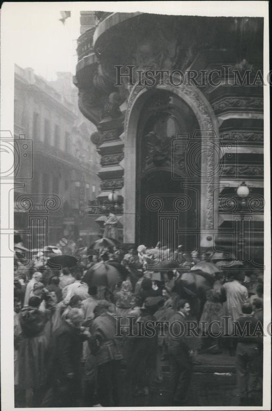 Press Photo Crowd Running To And Fro In the Rain Around Intricately Carved Bldgs - Historic Images